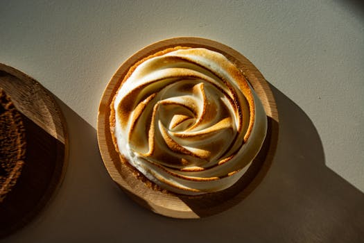 Tarte au chocolat avec ganache montée, meringue cacao et sablé fleur de sel, présentée sur une assiette en bois.